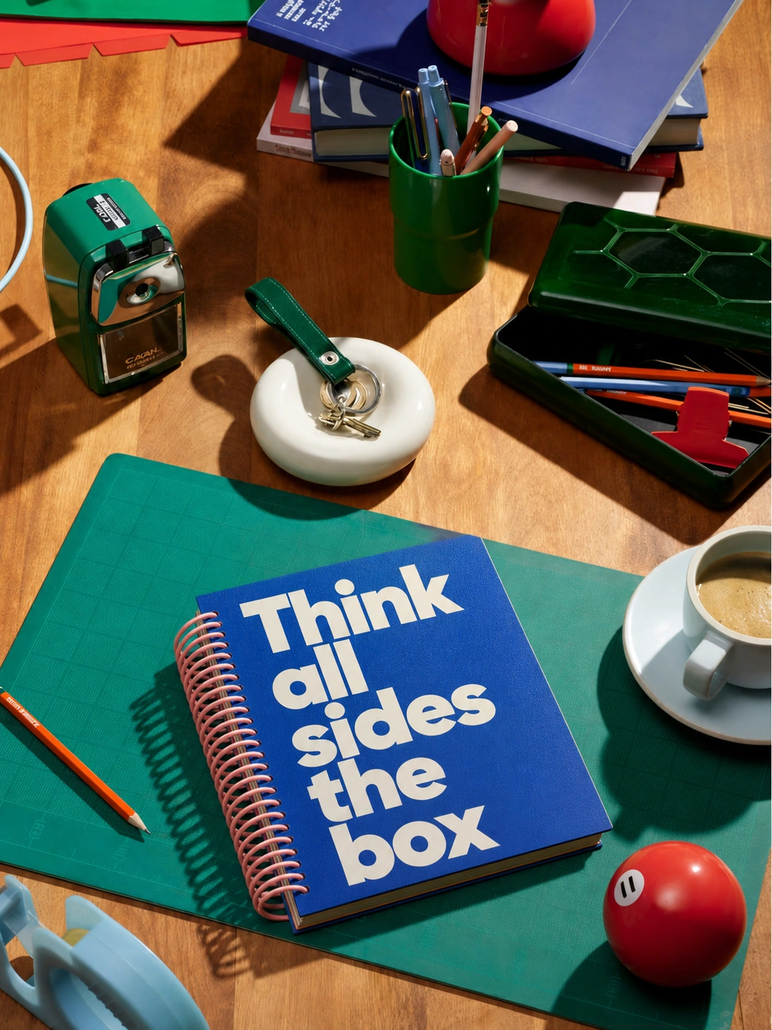 Mesa de trabalho criativa da Collab com caderno azul, materiais de papelaria e café